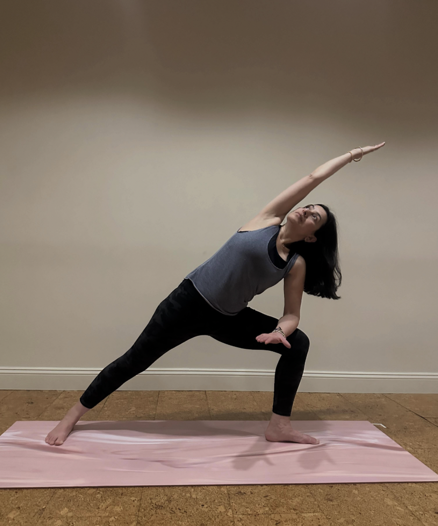 Neelam Vijh practicing an extended side angle yoga pose on a pink mat.