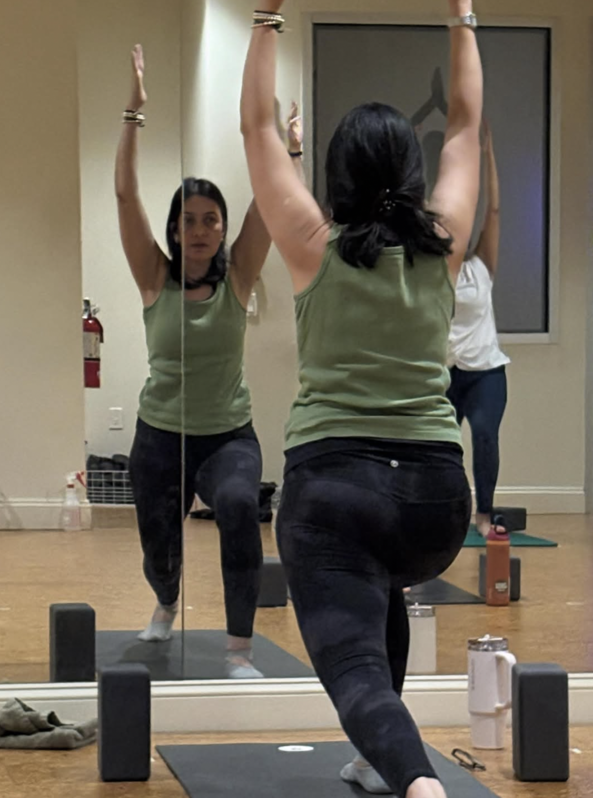 Neelam guiding a yoga class in a studio mirror.